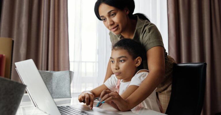 Mother Helping her Daughter use a Laptop